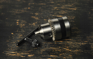 drill chuck and key on a dark wooden background dark photo