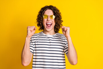 Photo portrait of nice teenager man raise fists scream excited win lottery wear trendy striped...