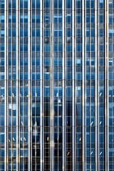 A modern architectural facade of a skyscraper with reflective glass windows - obrazy, fototapety, plakaty