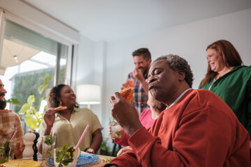 Man enjoying a pizza at a gathering of friends. Concept: enjoy, happiness, diversity