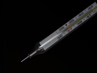 thermometer and a medical thermometer on a black background with the temperature