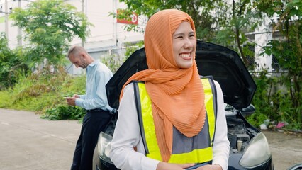 Adult female in high visibility vest smiling broadly, roadside, with young adult female and focused male in background by open car hood. Concept of taking care of car insurance after an accident.