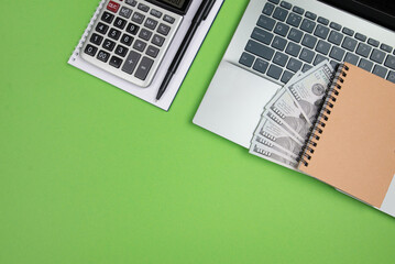 office desk with laptop calculator and other office supplies on isolated green background with copy space.
