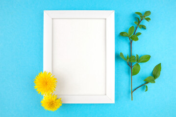 White wooden photo frame and flowers on blue background