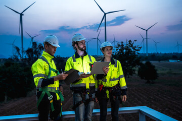Wind turbine engineer men and woman working in wind mill field at sunset