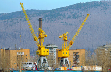Two harbor cranes in a port city.
