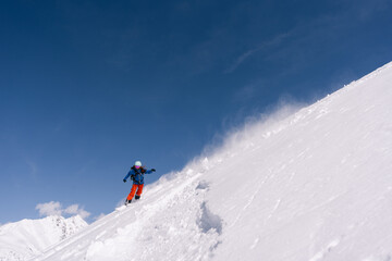 Fototapeta na wymiar Woman snowboarder riding on slope of powdery snow in high mountains. Freeride in avalanche-prone area, amazing mountain peaks view