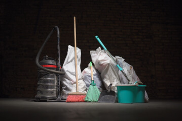 Broom, dust pan , bucket, mop, vacuum cleaner and trash bags garbage on the dirty dusty floor. Cleaning concept.