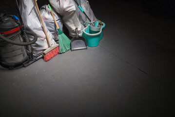 Broom, dust pan , bucket, mop, vacuum cleaner and trash bags garbage on the dirty dusty floor. Cleaning concept.