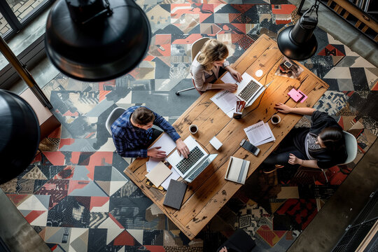 Aerial view of an openplan office space with three young professionals working around the large