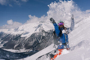 Woman snowboarder riding on slope of powdery snow in high mountains. Freeride at ski resort, Snow splashes trail,  mountain peaks view
