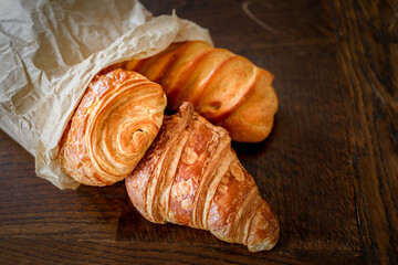 variety of french viennoiseries  in a paper bag on wooden surface