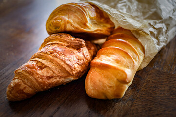 variety of french viennoiseries  in a paper bag on wooden surface