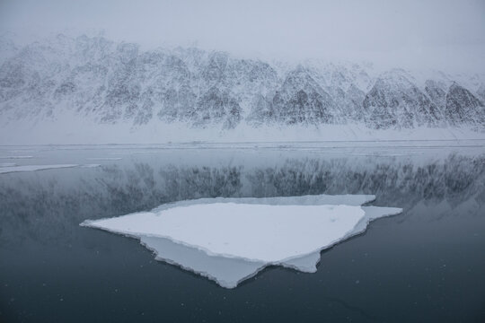 Double exposure shot of sheet of ice on Greenland Sea with snow covered mountains in background. Krossfjorden, Svalbard, Norway. April 2018. 