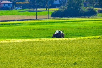 Farmer driving through a farmland in a tractor with a tractor sprayer