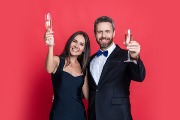 Elegant couple drink champagne isolated on red. Couple at formal occasion. Romantic date celebrations. Valentines day. Celebrate anniversary. Couple in love celebrate engagement. Cheers