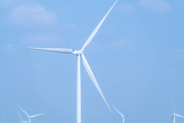 White wind turbines against a clear blue sky, symbolizing clean energy and sustainable technology.