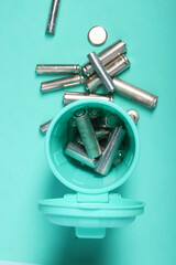 Visual metaphor for recycling electronics: small trash container holding gathered finger batteries, promoting a greener approach to waste management. Light green background.