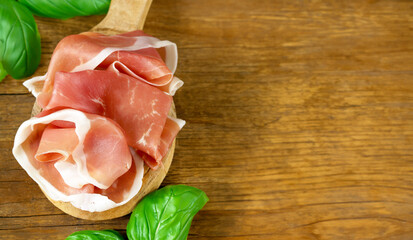 prosciutto ham on a wooden board with basil - 788519510