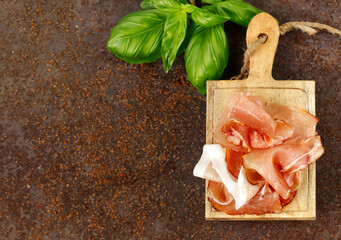 prosciutto ham on a wooden board with basil - 788519518
