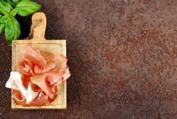 prosciutto ham on a wooden board with basil - 788519559