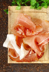 prosciutto ham on a wooden board with basil - 788519561