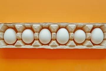 Foto op Plexiglas Six white eggs in egg carton on orange background, top view, flat lay © SHOTPRIME STUDIO
