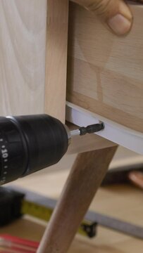 Handyman fixing over tight drawer slides rail of bedside table.