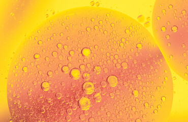 Beautiful cosmetic background. Golden orange yellow abstract oil bubbles or face serum background. Oil and water bubbles macro photography.