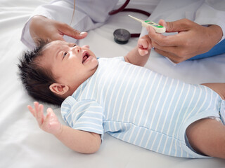 Baby illness medicine flu fever and thermometer, a doctor checks the temperature of the ill baby....