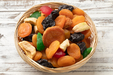 Basket with colorful dried fruit, tutti frutti, on wooden background close up