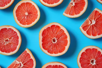 Plexiglas foto achterwand Fresh vibrant grapefruits arranged in a flat lay style on a bright blue background, top view © SHOTPRIME STUDIO