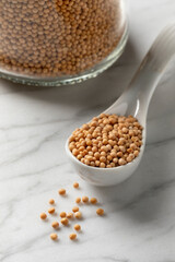 Spoon with a heap of dried organic white mustard seed close up