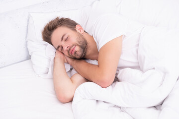Sleepy man lying on bed sleeping at white bedroom. Asleep young man sleeping. Resting peacefully in comfortable bed. Lying with closed eyes. Deep male sleep. Man sleeping at night. Tranquil night - 788533393