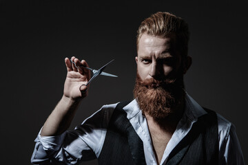 Bearded hipster barber isolated on black. Man beard haircut by hairdresser at barbershop. Handsome barber using scissors while cutting hair. Modern barbershop haircut
