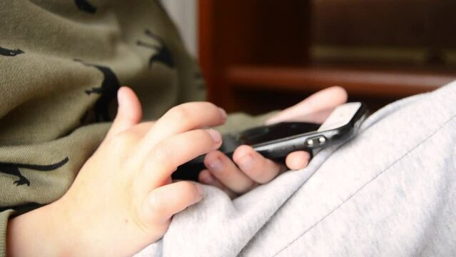 Boy using smartphone pressing finger.Child playing on smartphone closeup.