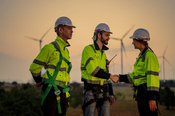 Team Engineers men and woman celebrating on construction site with sunset sky. people operation. Wind turbine for electrical of clean energy and environment. Industrial of sustainable.