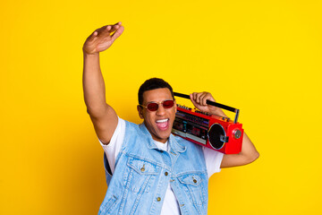 Photo of crazy funky guy dressed jeans waistcoat arm up enjoy music boombox on shoulder isolated on...