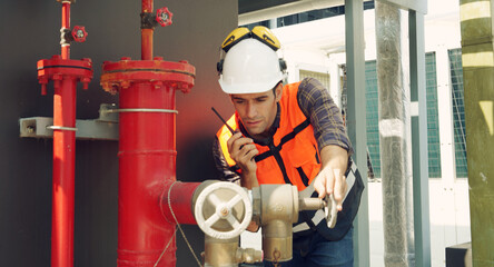 Foreman engineer wearing reflective jacket, engineering helmet, holding walkie-talkie, inspects...