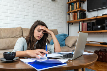 Young stressed woman having issue with utility bills expense, sitting at home trying to calculate and see bad finance bank report, searching for mistake. College student girl with money problem.