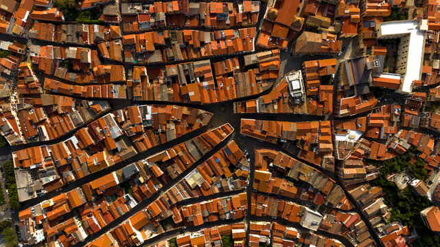 Aerial zenith view of the streets and alleys of the historic center of Iglesias, Italy. All houses have traditional red roofs.