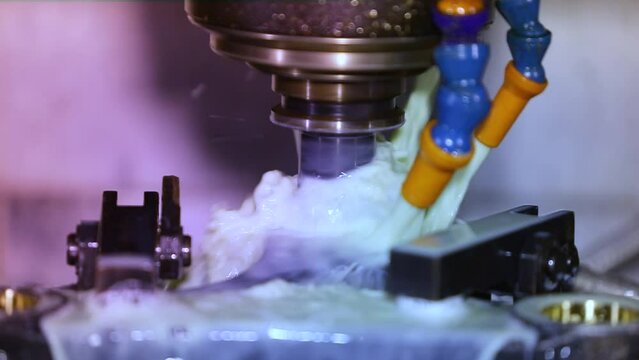 Close up of CNC grinding milling machine. CNC turning center. CNC machining high precision turning throwing coolant liquid on metal component during shaping forming process using machining center