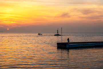 Sunset on the sea with boats and people on the pier