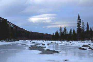 Icy river in a winter wonderland under a cloudy sky