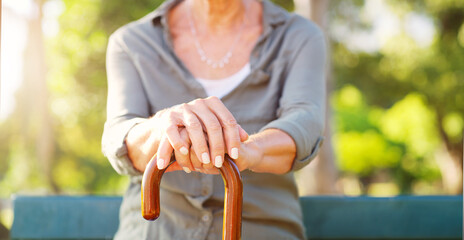Senior woman, park and hand with cane in nature for mobility support, healthcare and balance....