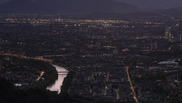 Turin, Italy. Panoramic view over the city from Superga hill. On the left the Po river and Murazzi. Mole Antonelliana dome in the centre. Day to Night 4K pan Timelapse video.