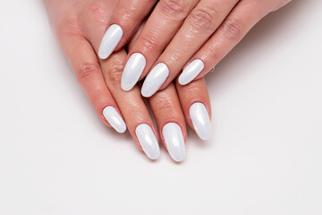 Wedding white pearl manicure on long oval nails close-up on a white background.