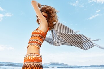 Summer Freedom: Smiling Beach Woman enjoying the Sea Breeze and Nature's Embrace with Curly Hair...