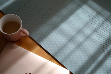 yoga mat and cup of green tea near the laptop, morning routine, sunlight on the floor