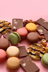 Pastel macarons, almond chocolate, peanut butter cookies and various nuts on bright pink...